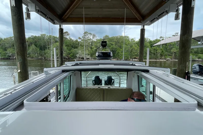 Slide: The Image of 2021 Axopar 28 Cabin boat docked under a wooden shelter by a scenic river. - 41