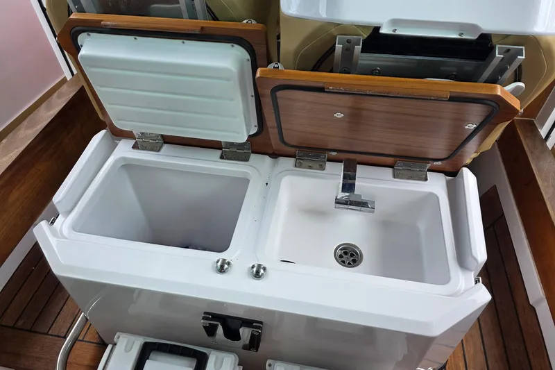 Slide: The Image of 2021 Axopar 28 Cabin boat sink and storage compartments with wooden accents. - 42