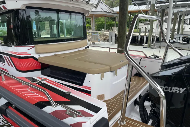 Slide: The Image of 2021 Axopar 28 Cabin boat with red and black accents, docked near a marina. - 9