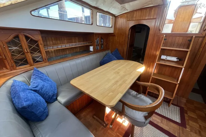 Slide: The Image of Interior of a 1979 Hardin 44 sailboat with wooden dining area and blue cushions. - 5