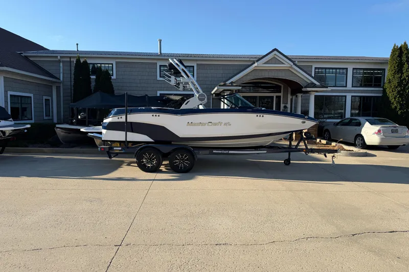 The Image of 2026 MasterCraft NXT20 boat on trailer, parked outside a modern building. - 0
