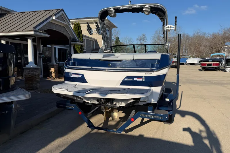 Slide: The Image of 2026 MasterCraft NXT20 boat on trailer, parked outdoors under clear blue sky. - 2