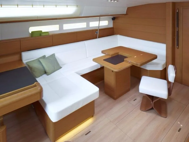 Slide: The Image of Manufacturer Provided Image: Interior of 2016 Jeanneau Sun Odyssey 519 sailboat with white seating and wooden table. - 7