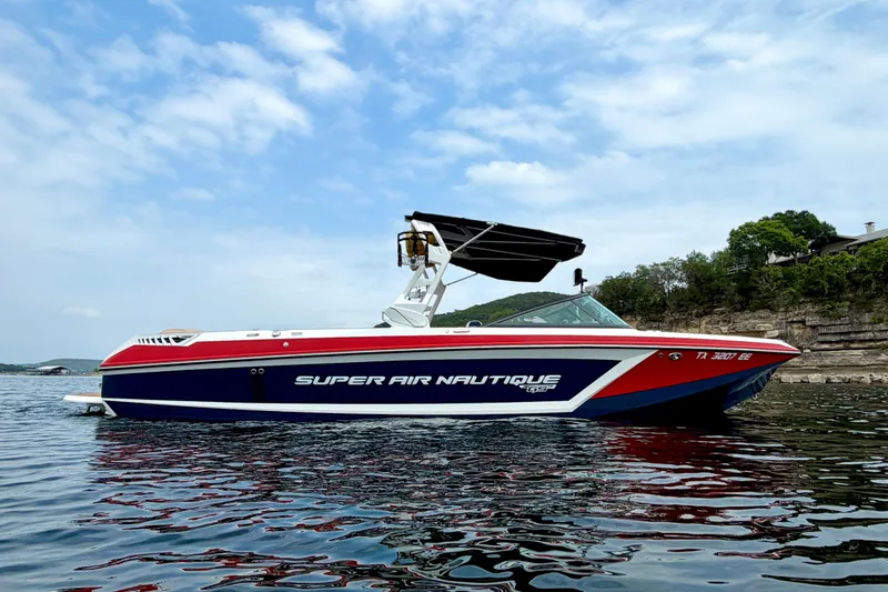 The Image of 2018 Nautique Super Air Nautique GS24 boat on water, under a partly cloudy sky. - 1