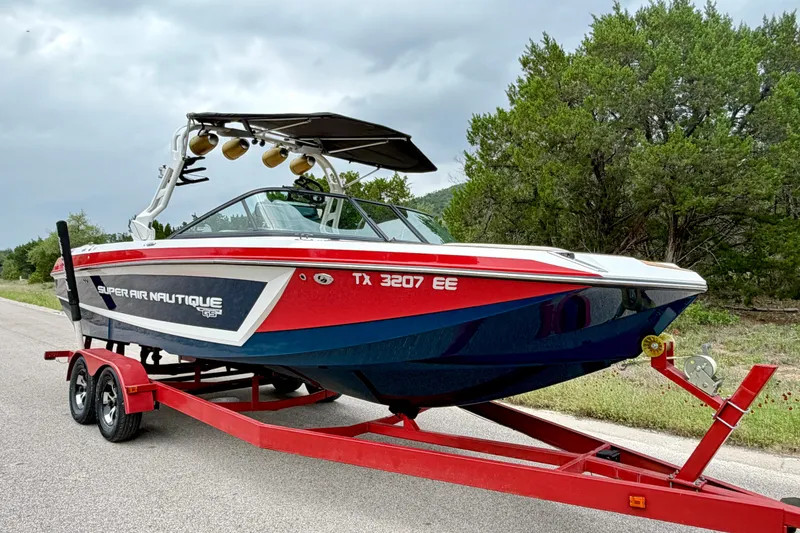 Slide: The Image of 2018 Nautique Super Air Nautique GS24 boat on red trailer, parked roadside. - 11