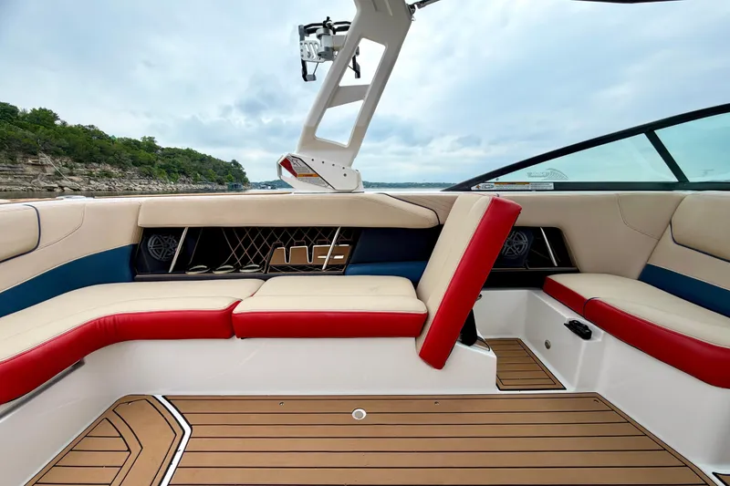 Slide: The Image of 2018 Nautique Super Air Nautique GS24 interior with red and beige seating, lake view. - 23
