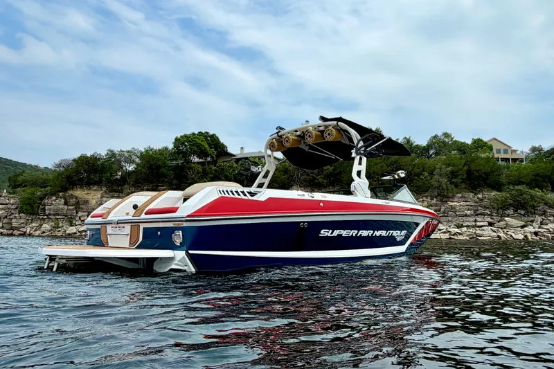 Slide: The Image of 2018 Nautique Super Air Nautique GS24 boat on a scenic lake with rocky shoreline. - 3