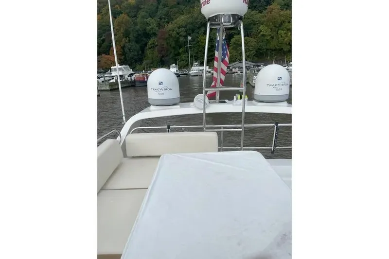 Slide: The Image of 2014 Azimut 45 yacht deck with seating, table, and American flag in marina setting. - 88