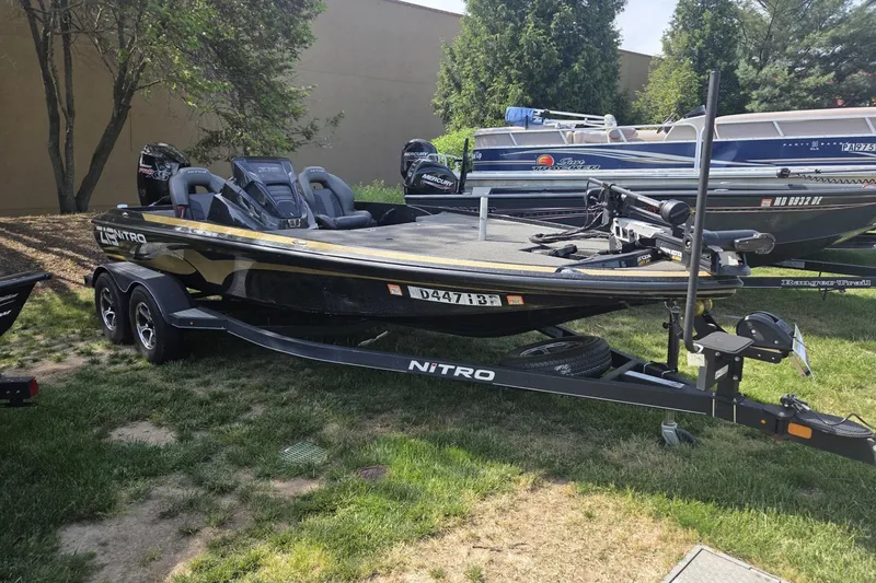 The Image of 2021 Nitro Z19 Pro boat on trailer, parked on grass, surrounded by trees and other boats. - 1