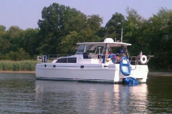 Slide: The Image of 1999 Endeavour Trawlercat 36 on calm water, surrounded by lush greenery. - 2