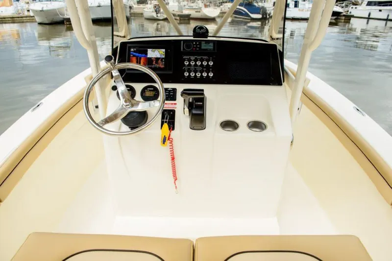 Slide: The Image of Manufacturer Provided Image: 2025 Scout 215 XSF boat console with steering wheel and controls at marina. - 11