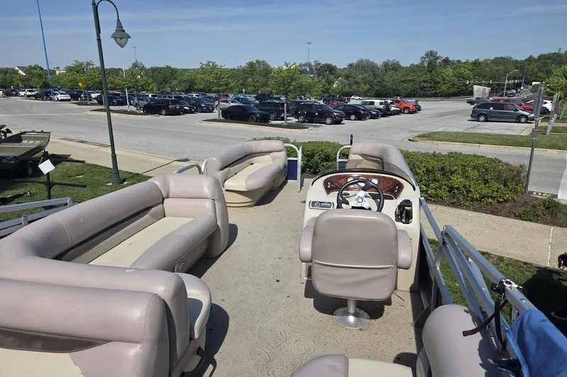 Slide: The Image of 2014 Sun Tracker Party Barge 24 pontoon boat with beige seating, parked near a lot. - 7