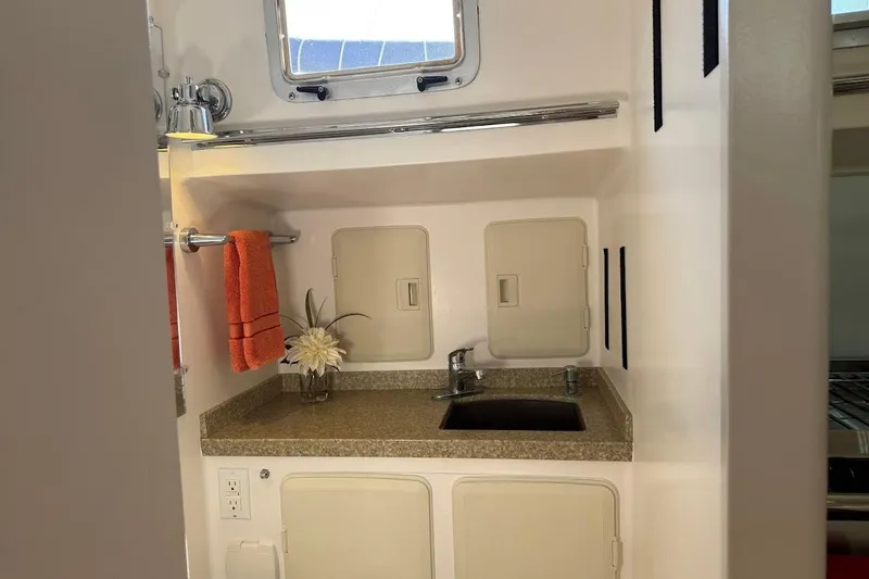 Slide: The Image of Compact bathroom sink area in a 2011 Reliance 44 yacht, featuring orange towel and flower. - 13