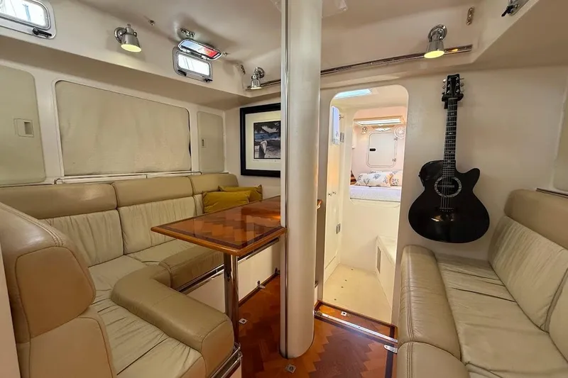 Slide: The Image of Luxurious 2011 Reliance 44 yacht interior with leather seating, wooden table, and mounted guitar. - 2
