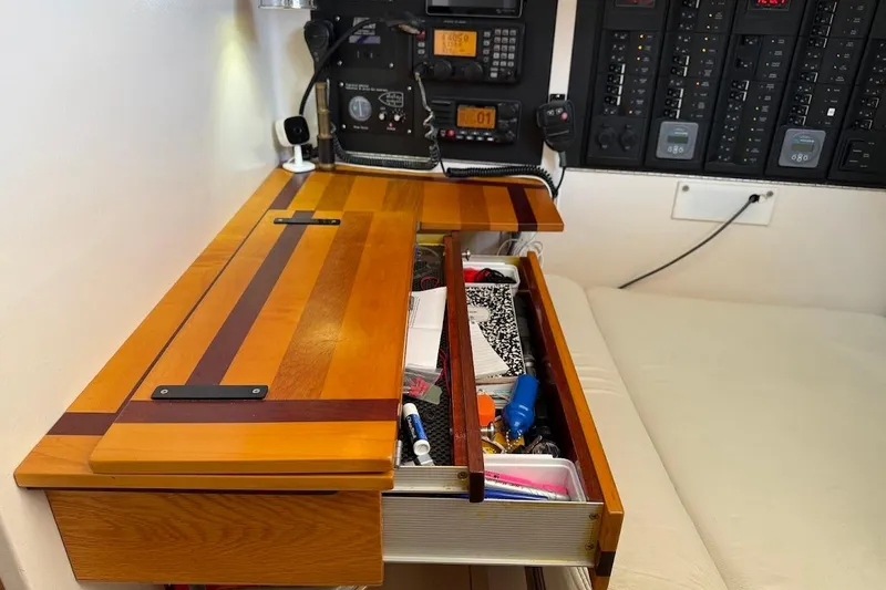 Slide: The Image of Wooden desk with open drawer, revealing various items, in a 2011 Reliance 44 boat interior. - 23