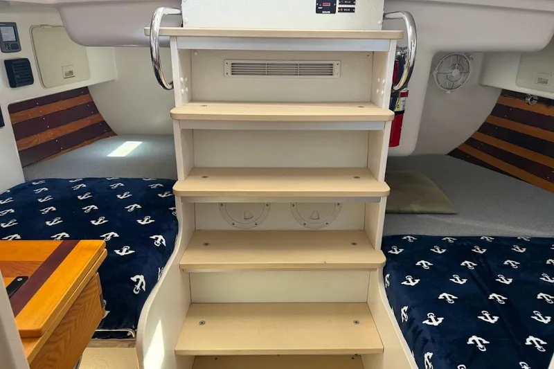 Slide: The Image of Interior of 2011 Reliance 44 boat with wooden steps and nautical-themed bedding. - 25
