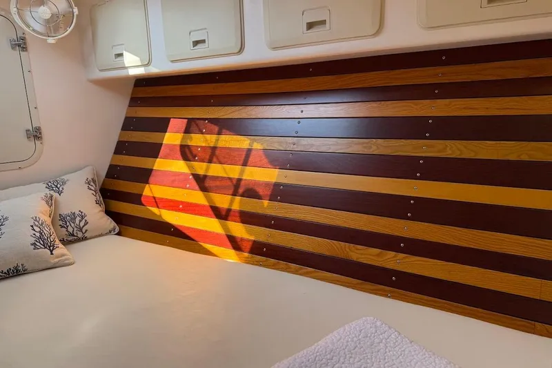 Slide: The Image of Cozy boat cabin interior with striped wood paneling, pillows, and a small fan. - 7