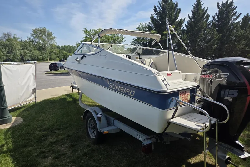 Slide: The Image of 1995 Sunbird Corsair boat on trailer with Mercury engine, parked on grass. - 8