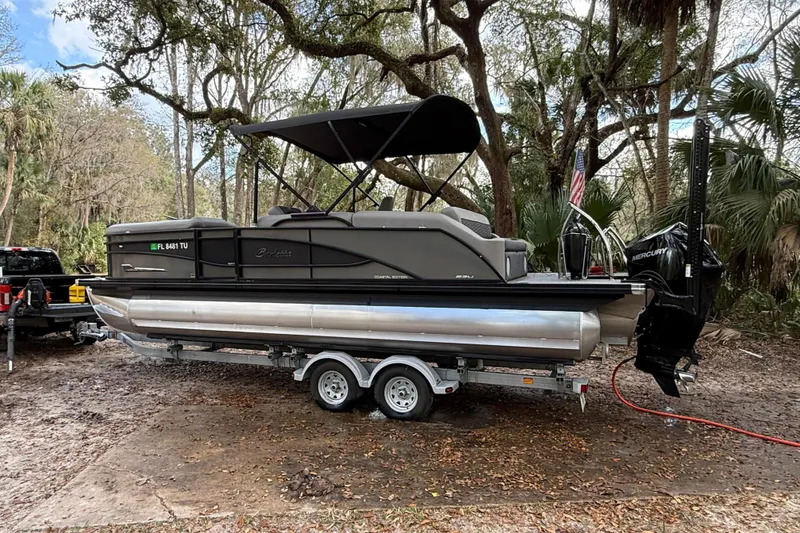 The Image of 2023 Barletta Corsa 23U pontoon boat on trailer in wooded area. - 0