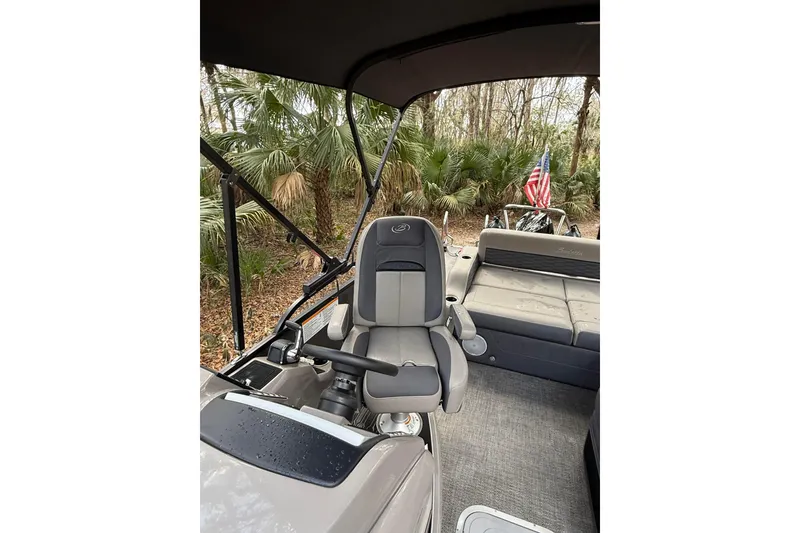 Slide: The Image of 2023 Barletta Corsa 23U boat interior with seating and American flag in wooded setting. - 6