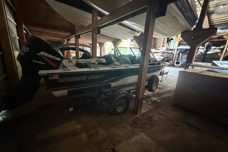 Slide: The Image of 1994 Smoker Craft 182 Pro Mag boat with Mercury engine in a wooden storage area. - 6