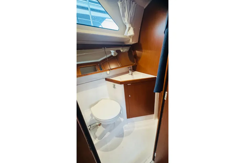 Slide: The Image of 2018 Beneteau Oceanis 41.1 yacht bathroom with toilet, sink, and wooden cabinetry. - 14
