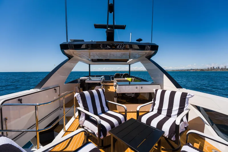 Slide: The Image of Luxurious 2024 Pearl 72 yacht deck with striped chairs, ocean view, and clear blue sky. - 111