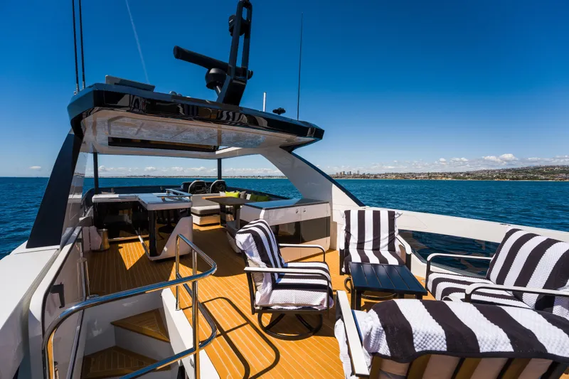 Slide: The Image of Luxurious 2024 Pearl 72 yacht deck with striped chairs, ocean view, and clear blue sky. - 112