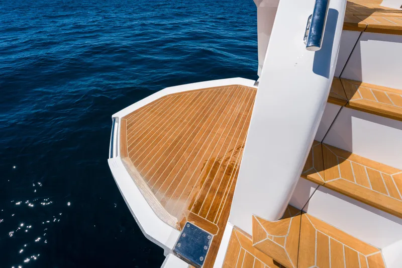 Slide: The Image of Luxury yacht Pearl 72, 2024 model, featuring elegant wooden deck and stairs by the ocean. - 79