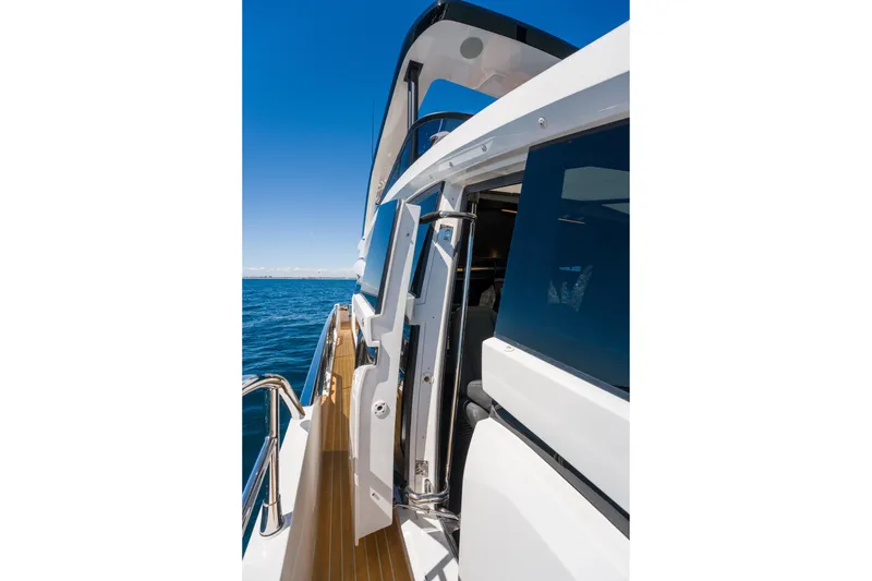 Slide: The Image of 2024 Pearl 72 yacht deck with open door, overlooking the ocean under clear blue sky. - 97