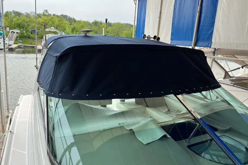 Slide: The Image of 1997 Bayliner 4085 Avanti with blue canopy docked at marina. - 42