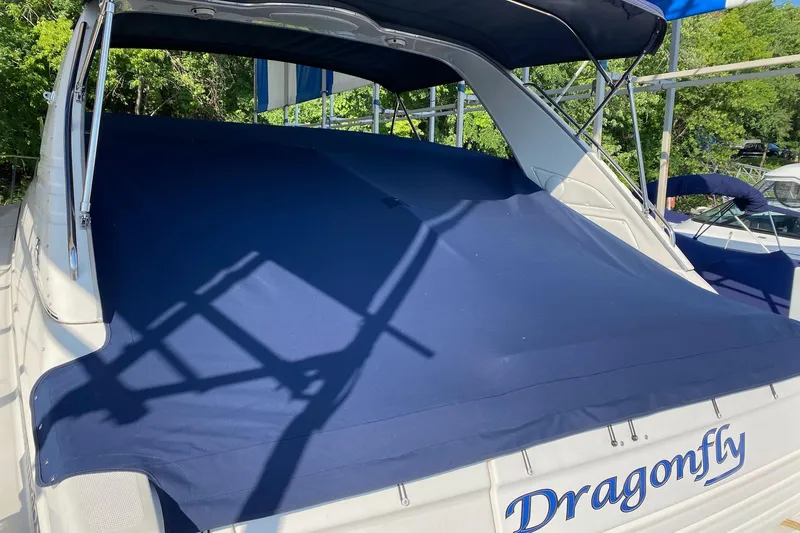 Slide: The Image of 1997 Bayliner 4085 Avanti boat with blue cover, named "Dragonfly," docked outdoors. - 47