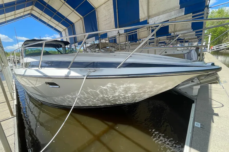 Slide: The Image of 1997 Bayliner 4085 Avanti docked under a canopy, reflecting sunlight on the water. - 5