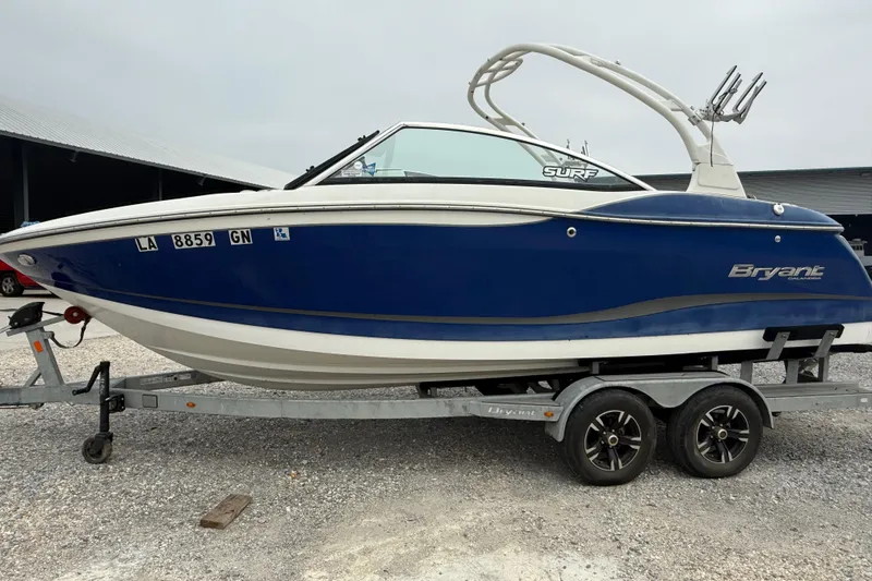 Slide: The Image of 2018 Bryant Calandra boat on trailer, blue and white design, parked outdoors. - 7