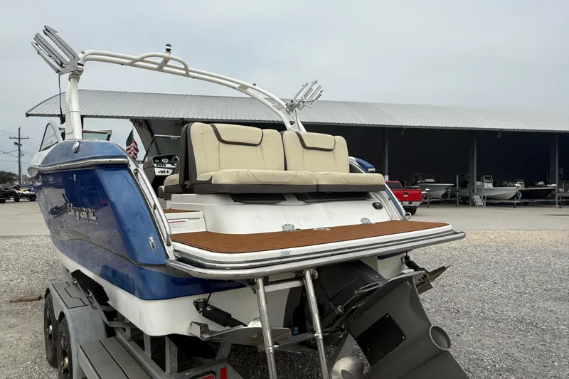 Slide: The Image of 2018 Bryant Calandra boat with blue hull on trailer, featuring rear seating and swim platform. - 9