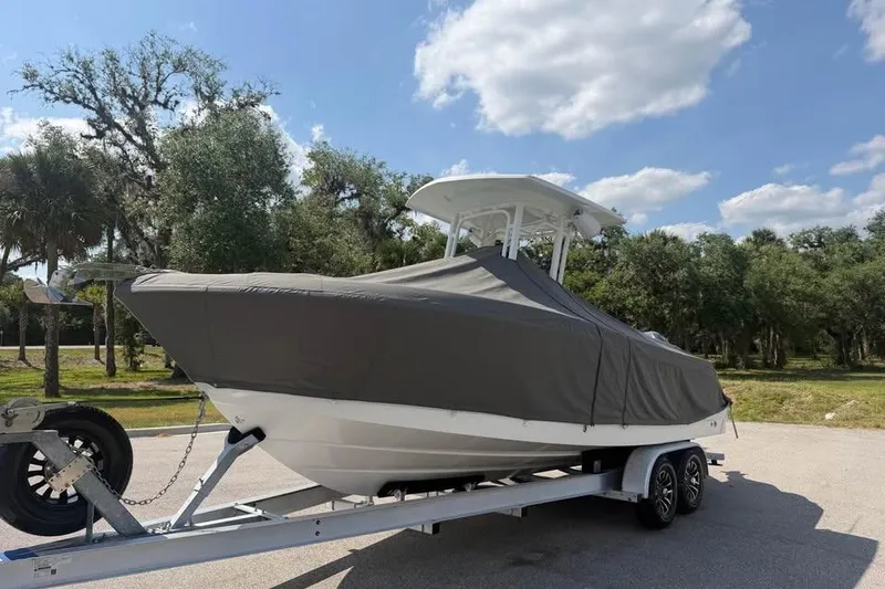 Slide: The Image of 2018 Robalo R242 Center Console boat covered on trailer, parked outdoors. - 20