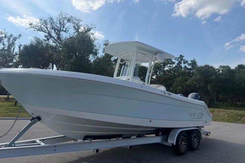 Slide: The Image of 2018 Robalo R242 Center Console boat on trailer, parked outdoors under a clear sky. - 3