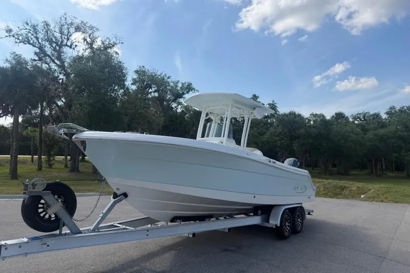 Slide: The Image of 2018 Robalo R242 Center Console boat on trailer, parked outdoors under blue sky. - 6