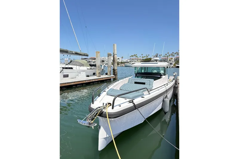 Slide: The Image of 2022 Axopar 37 XC Cross Cabin docked in a marina under clear blue skies. - 2
