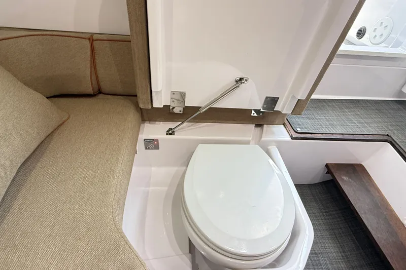 Slide: The Image of 2022 Axopar 37 XC Cross Cabin interior with compact toilet and beige seating. - 24