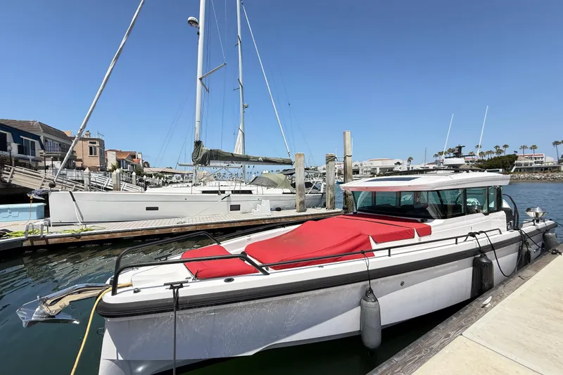 Slide: The Image of 2022 Axopar 37 XC Cross Cabin docked at a marina with sailboats nearby. - 4
