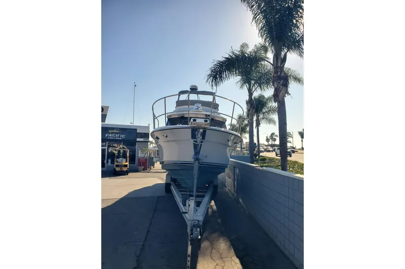 Slide: The Image of 2024 Cutwater C-30 CB boat on trailer, parked near palm trees and dealership. - 1