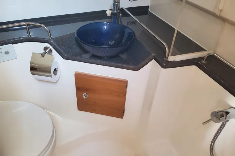 Slide: The Image of 2024 Cutwater C-30 CB bathroom with blue sink, toilet, and wooden cabinet. - 16