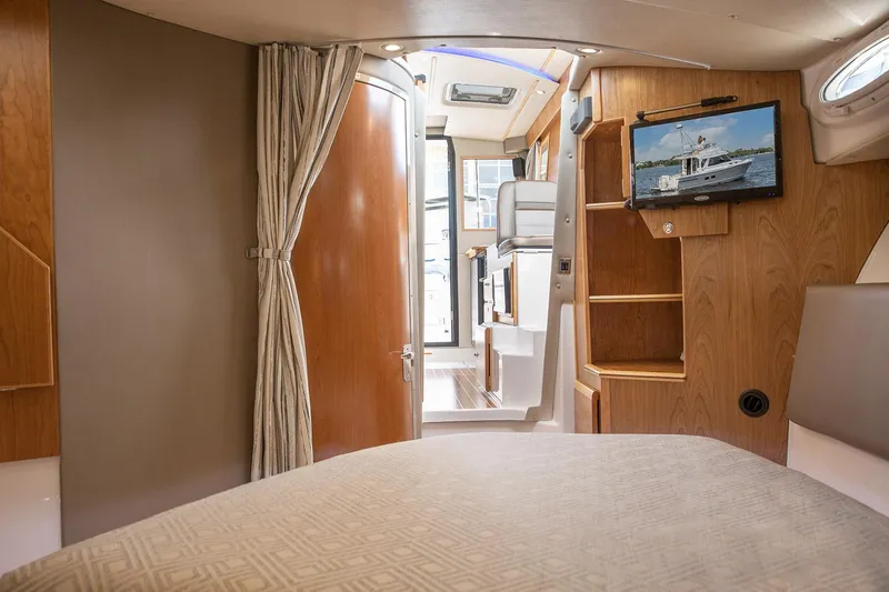 Slide: The Image of Manufacturer Provided Image: 2024 Cutwater C-30 CB cabin interior with TV, bed, and wooden finishes. - 33