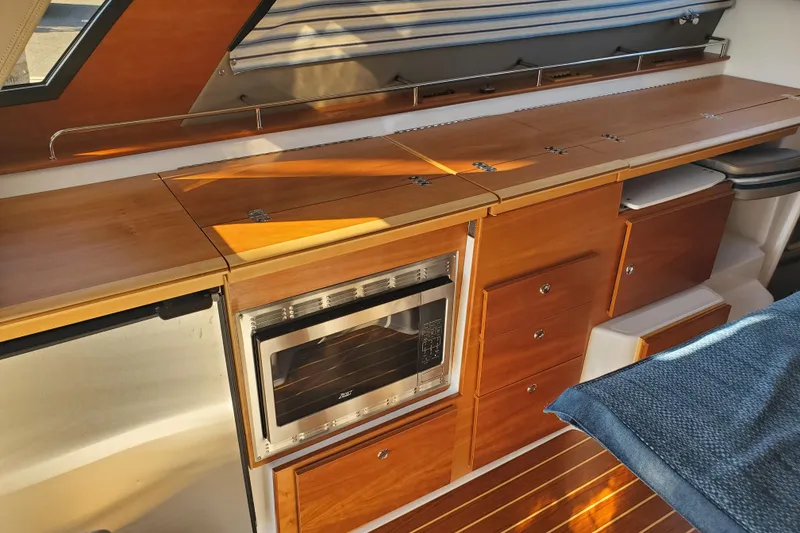 Slide: The Image of 2024 Cutwater C-30 CB interior kitchen with wooden cabinetry, microwave, and sleek design. - 8