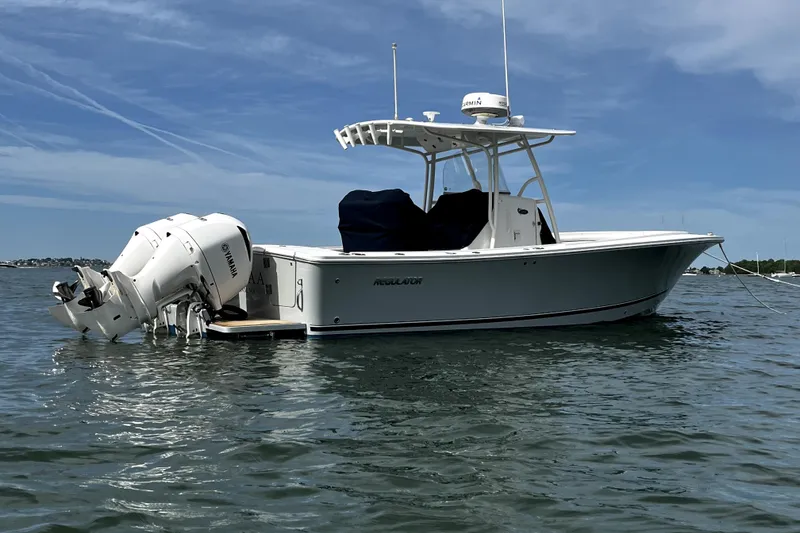 Slide: The Image of 2017 Regulator 28 Forward Seating boat on calm water under blue sky. - 2