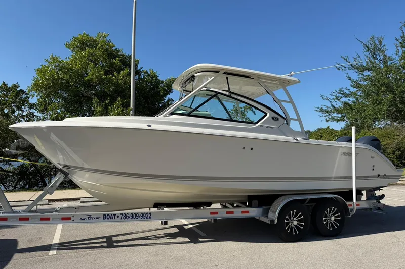 The Image of 2021 Pursuit DC 266 Dual Console boat on trailer, parked outdoors. - 1