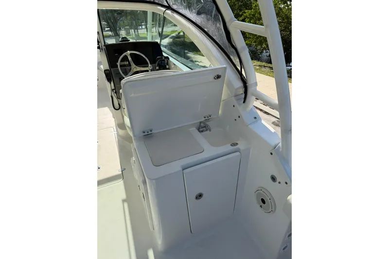 Slide: The Image of 2021 Pursuit DC 266 Dual Console boat interior with steering wheel and storage compartment. - 19