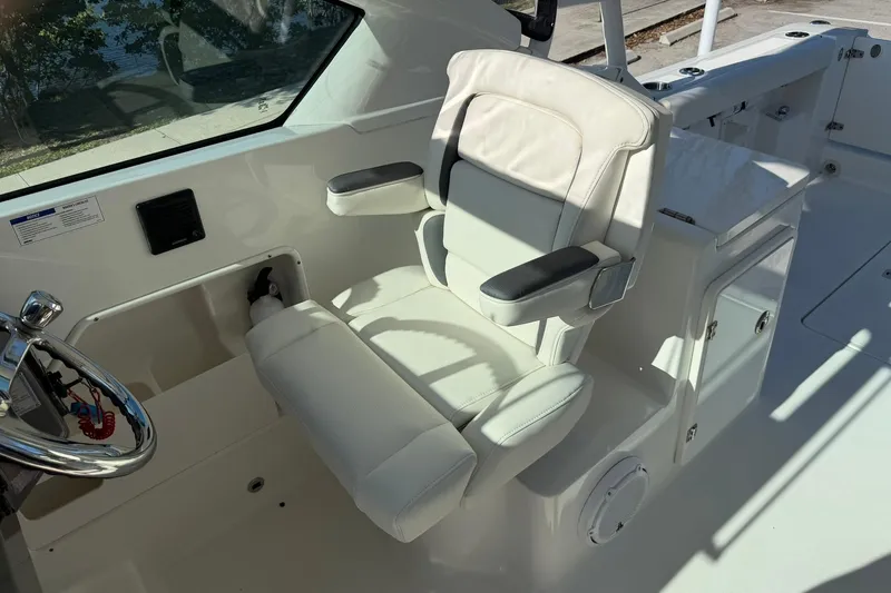 Slide: The Image of 2021 Pursuit DC 266 Dual Console boat interior with white captain's chair and steering wheel. - 21