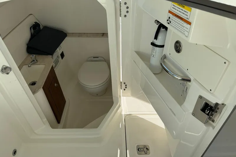 Slide: The Image of 2021 Pursuit DC 266 Dual Console boat interior with compact bathroom and sink. - 36